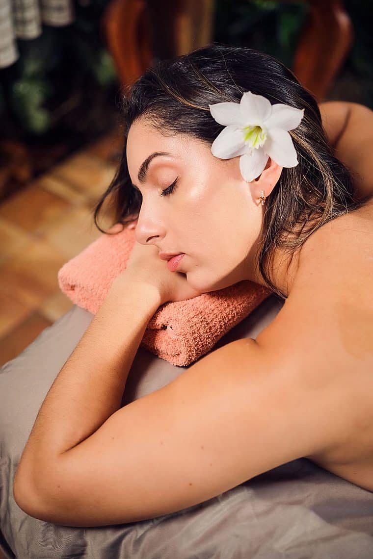 Clienta relajándose en la camilla con una flor blanca en el cabello