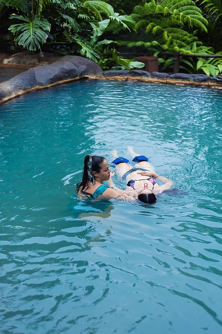 Terapeuta sosteniendo a una persona que flota boca arriba en agua tibia